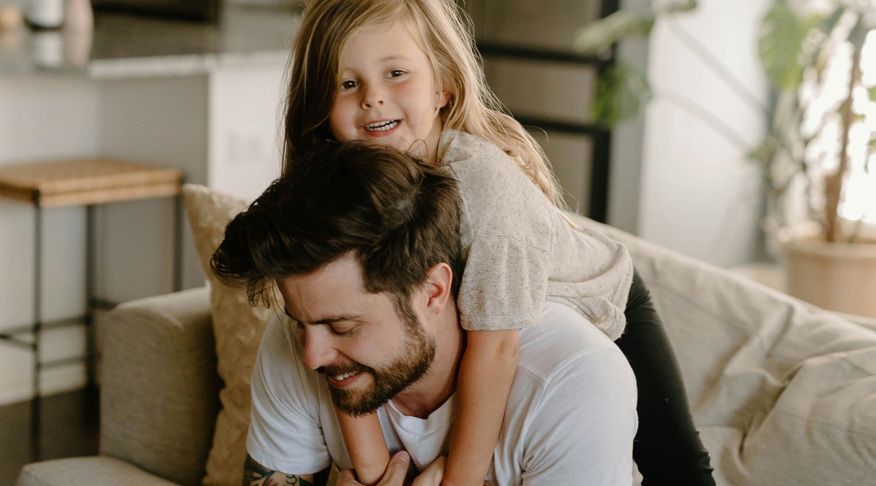 a father and daughter playing on a couch