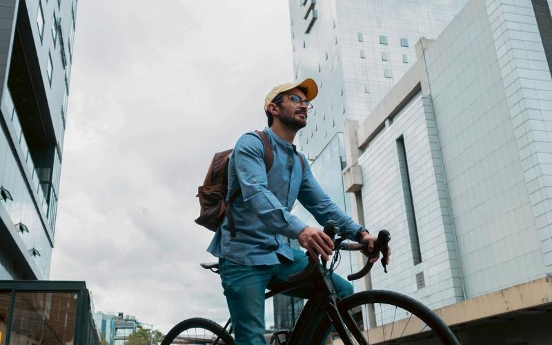 A man with a backpack riding a bicycle in the city.
