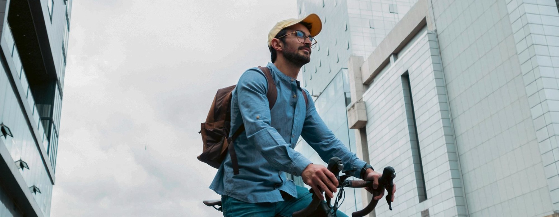 A man with a backpack riding a bicycle in the city.